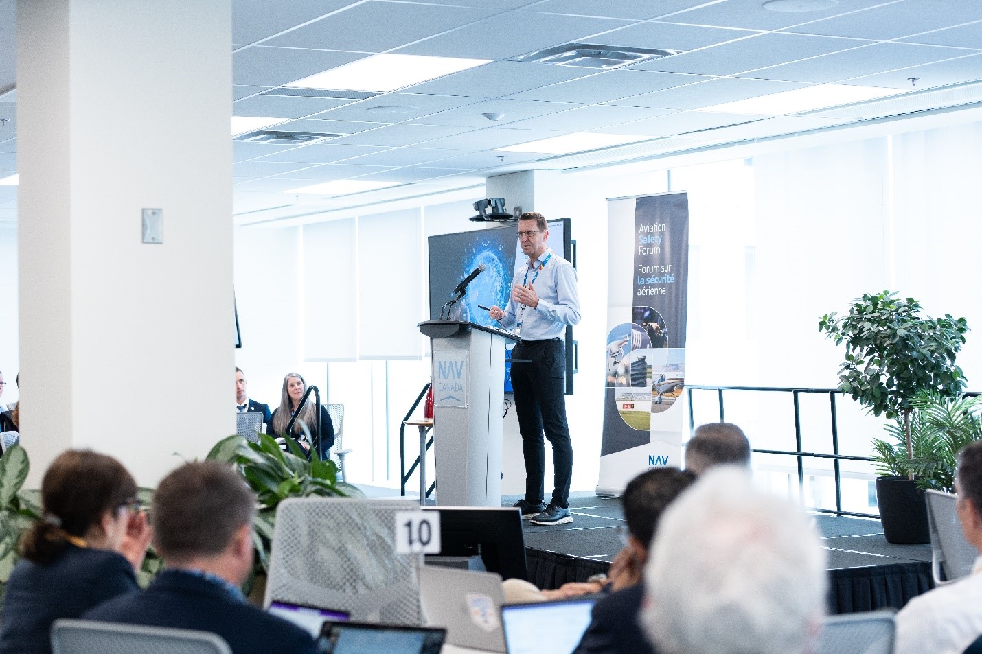 Man giving speech to audience in conference room.